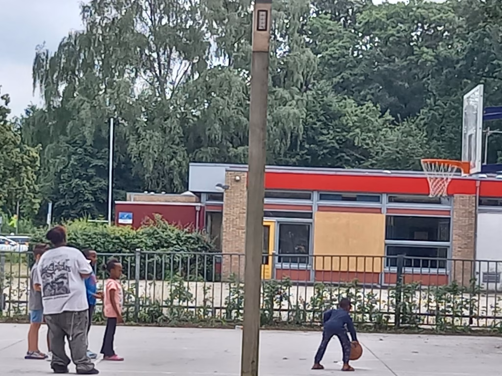 Kinderen spelen basketbal op het buitenveld bij Buurthuis Bronveld tijdens de Buitenspeeldag op 17 juni 2026