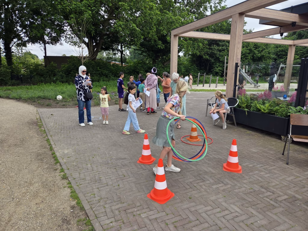Meisje hoelahoept tussen pionnen bij Buurthuis Bronveld tijdens de Buitenspeeldag op 17 juni 2026 - kun jij de hoelahoep om de pion heen gooien?
