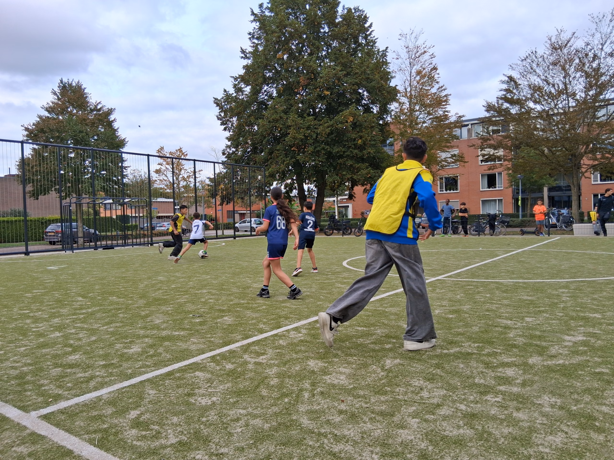 Kinderen voetballen op het kunstgrasveld tijdens het straten-voetbaltoernooi